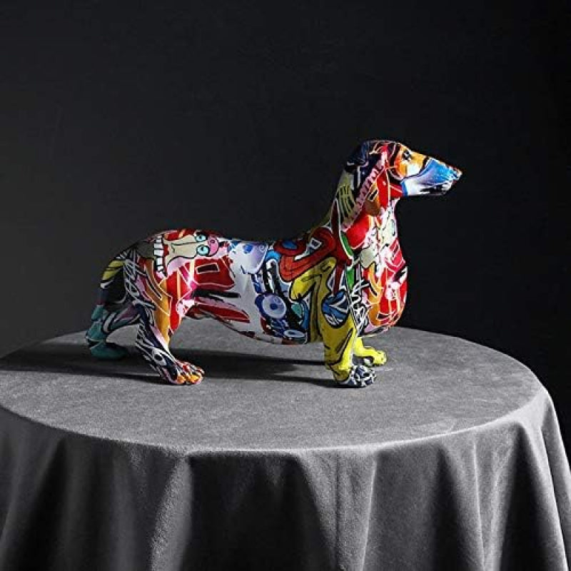 Una escultura decorativa de un perro salchicha, diseñada como grafiti, perfecta para realzar la estética de tu sala, dormitorio, estantería, mueble de televisión o escritorio. Sirve como un encantador centro de mesa o adorno.